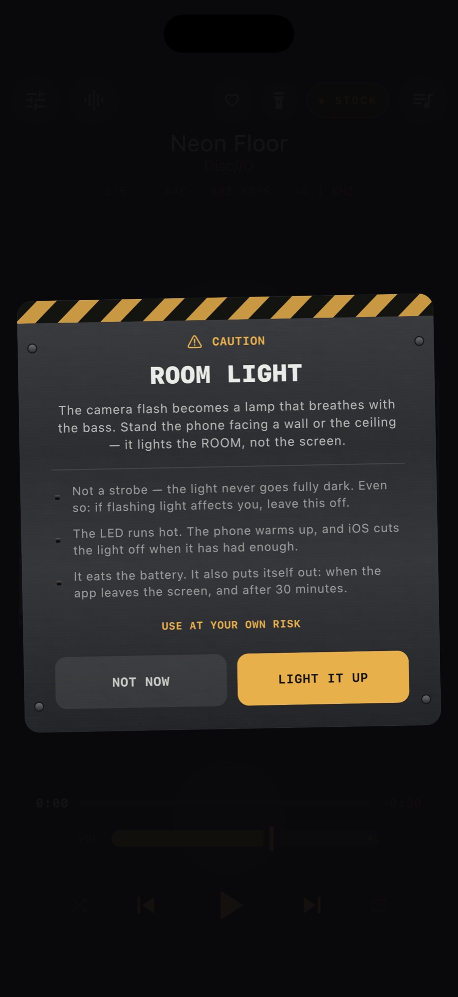 The MP95 Room Light caution plate: a riveted metal panel with a hazard stripe explaining that the camera flash becomes a lamp that breathes with the bass, is not a strobe, runs hot and puts itself out, with NOT NOW and LIGHT IT UP keys
